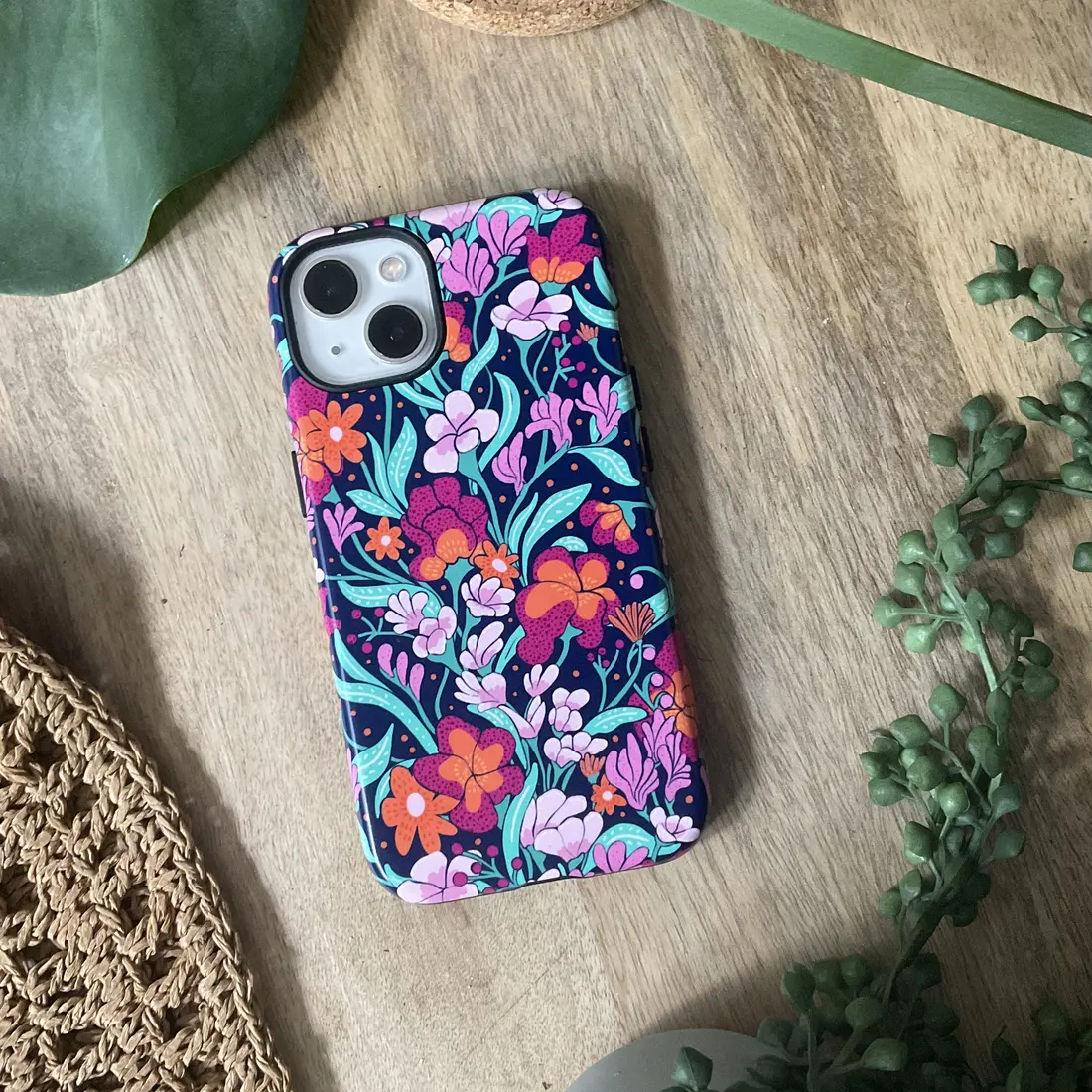 Phone case in a navy floral pattern with orange and pink blooms