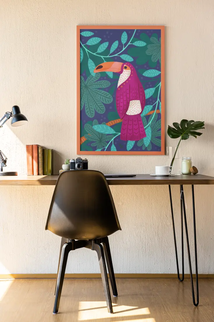 Framed toucan print hanging above a desk